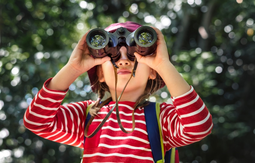 Preschool child looking through binoculars watching for birds