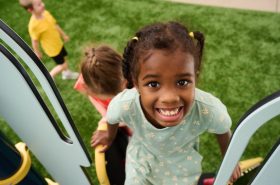 Preschool girl staying active by playing on playground in New Horizon Academy's summer program