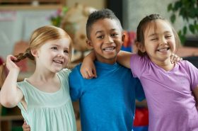 Diverse group of children hugging in their childcare classroom