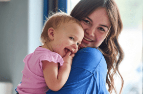 Infant teacher hugging infant child at New Horizon Academy